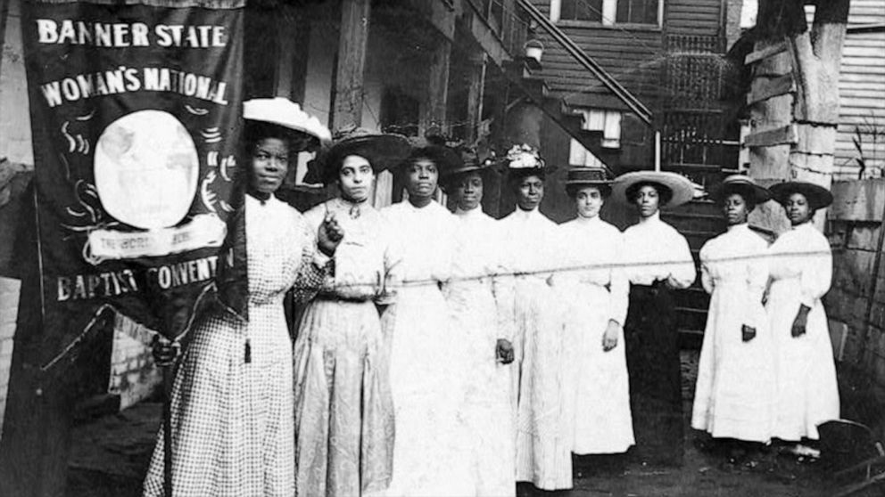 Nine African-American women pose for a photo with Nannie Burroughs, holding a banner that reads, "Banner State Woman's National Baptist Convention," circa 1905.
